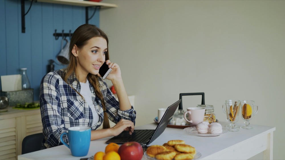 A woman on the phone at her kitchen table