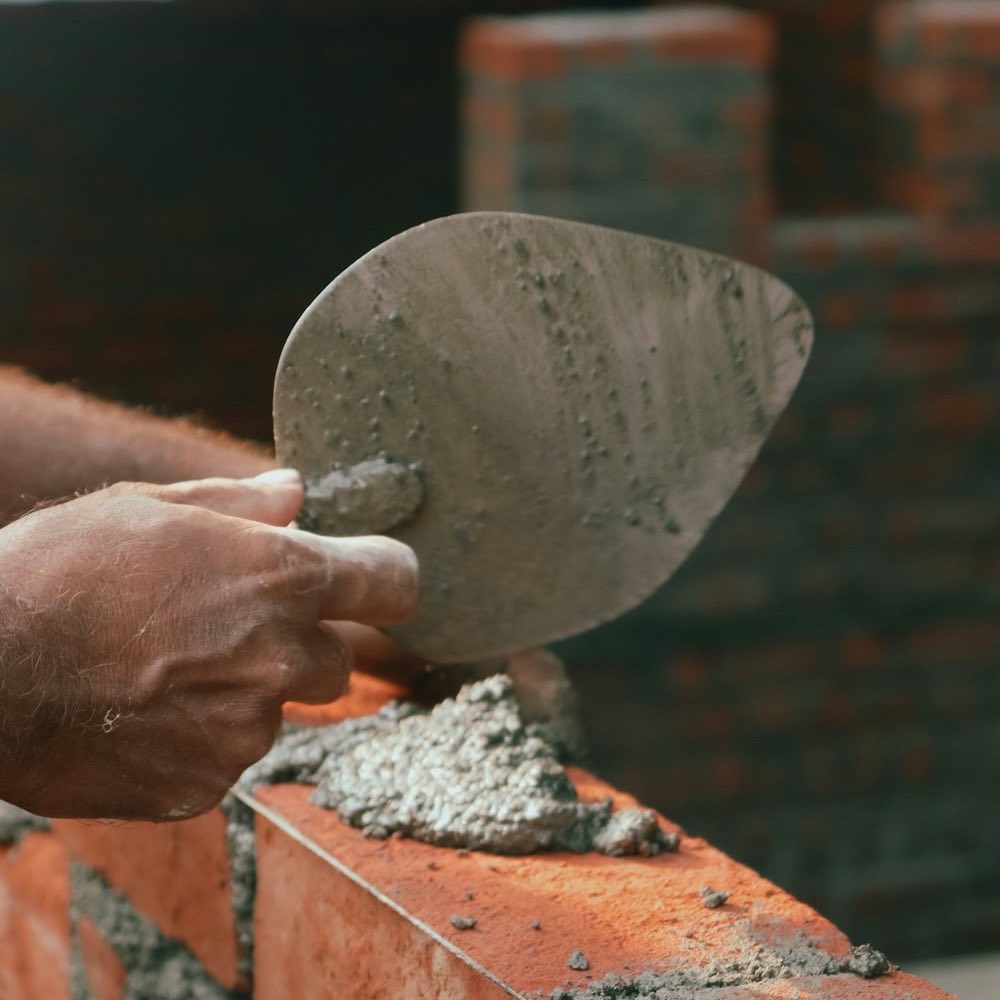 A trowel laying mortar on a brick wall
