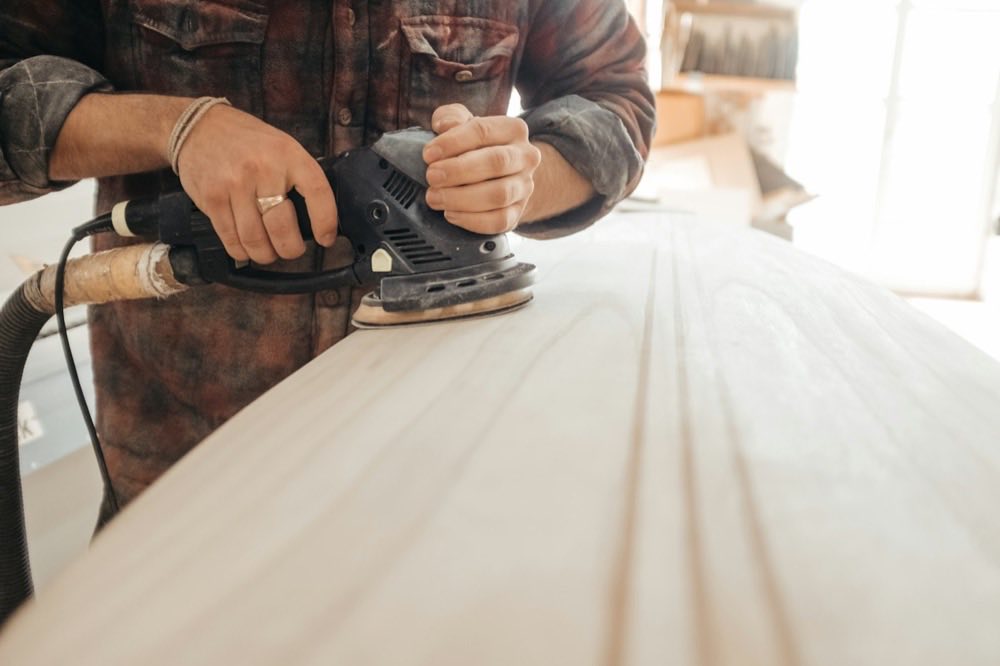 Hands sanding a length of timber